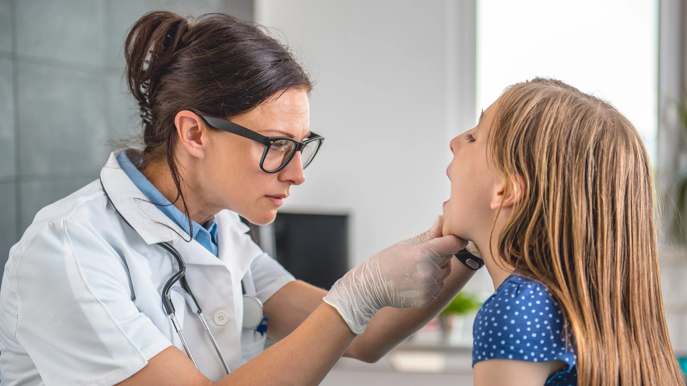 Doctor examining a little girl's mouth and teeth.