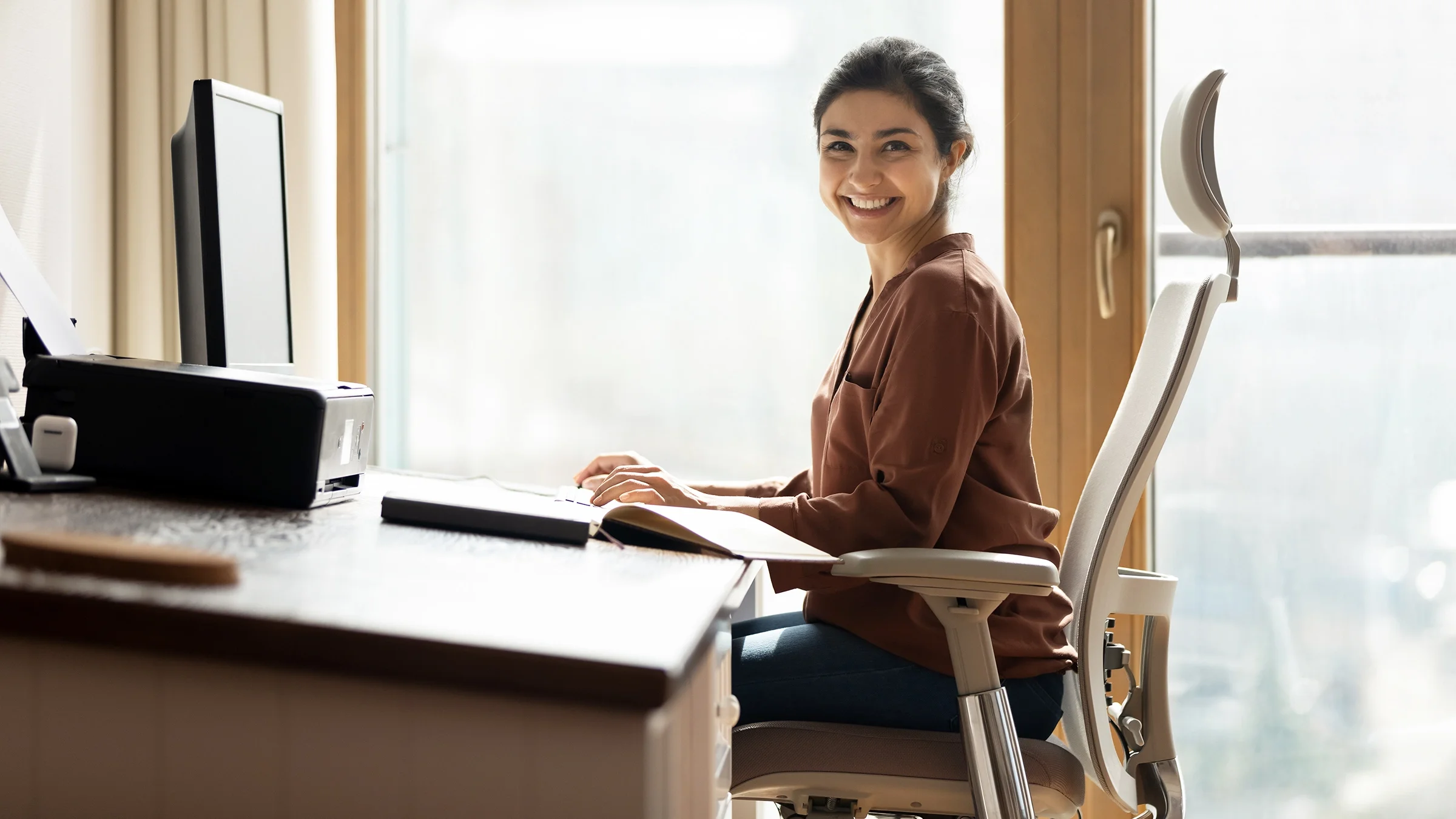 Portrait of woman sitting by a computer in ergonomic office chair.