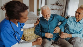 Health: GERD: senior man showing nurse pain area-1345847711