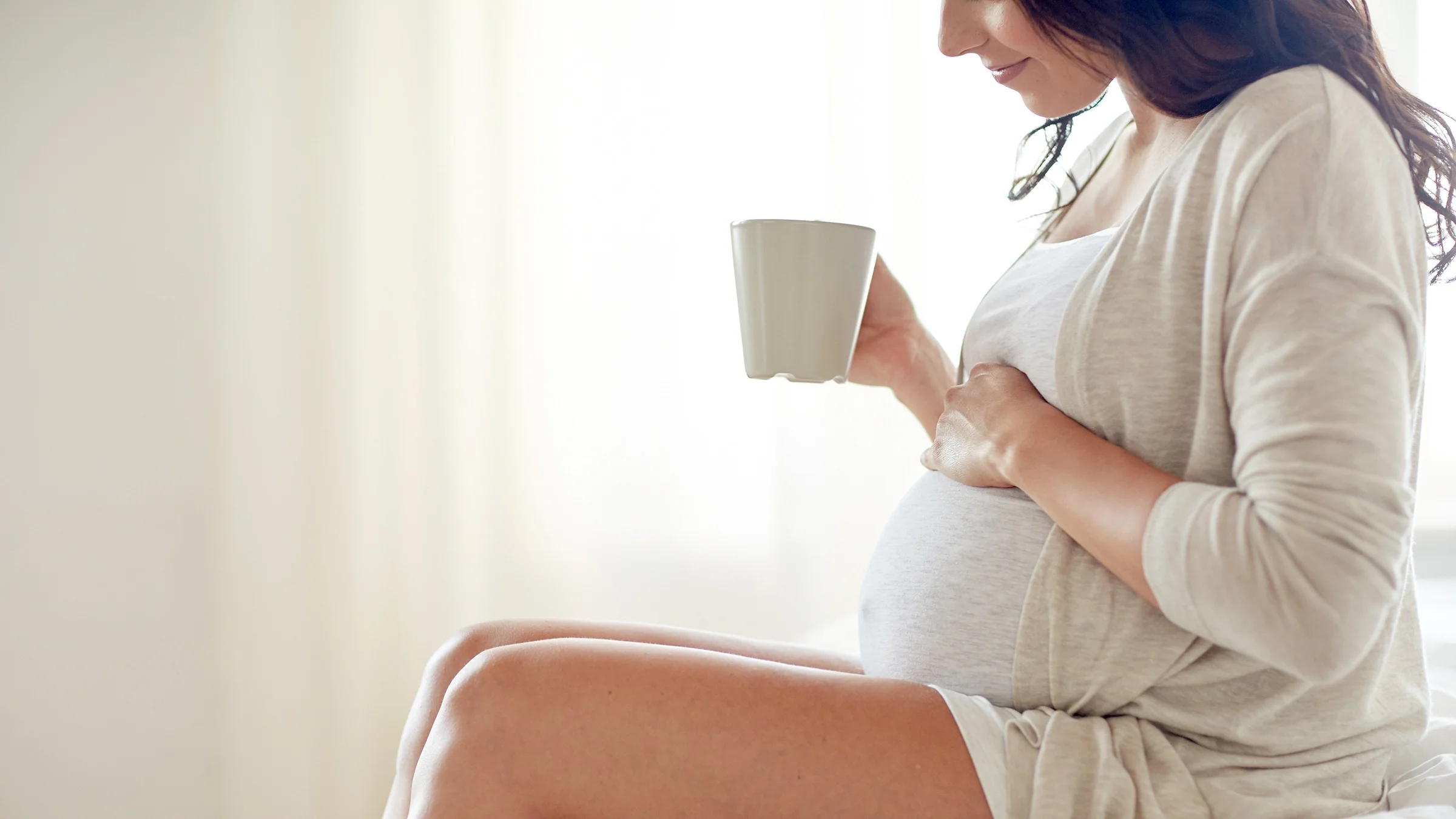 A pregnant woman drinks a cup of coffee. Untreated celiac disease can lead to problems during pregnancy.
