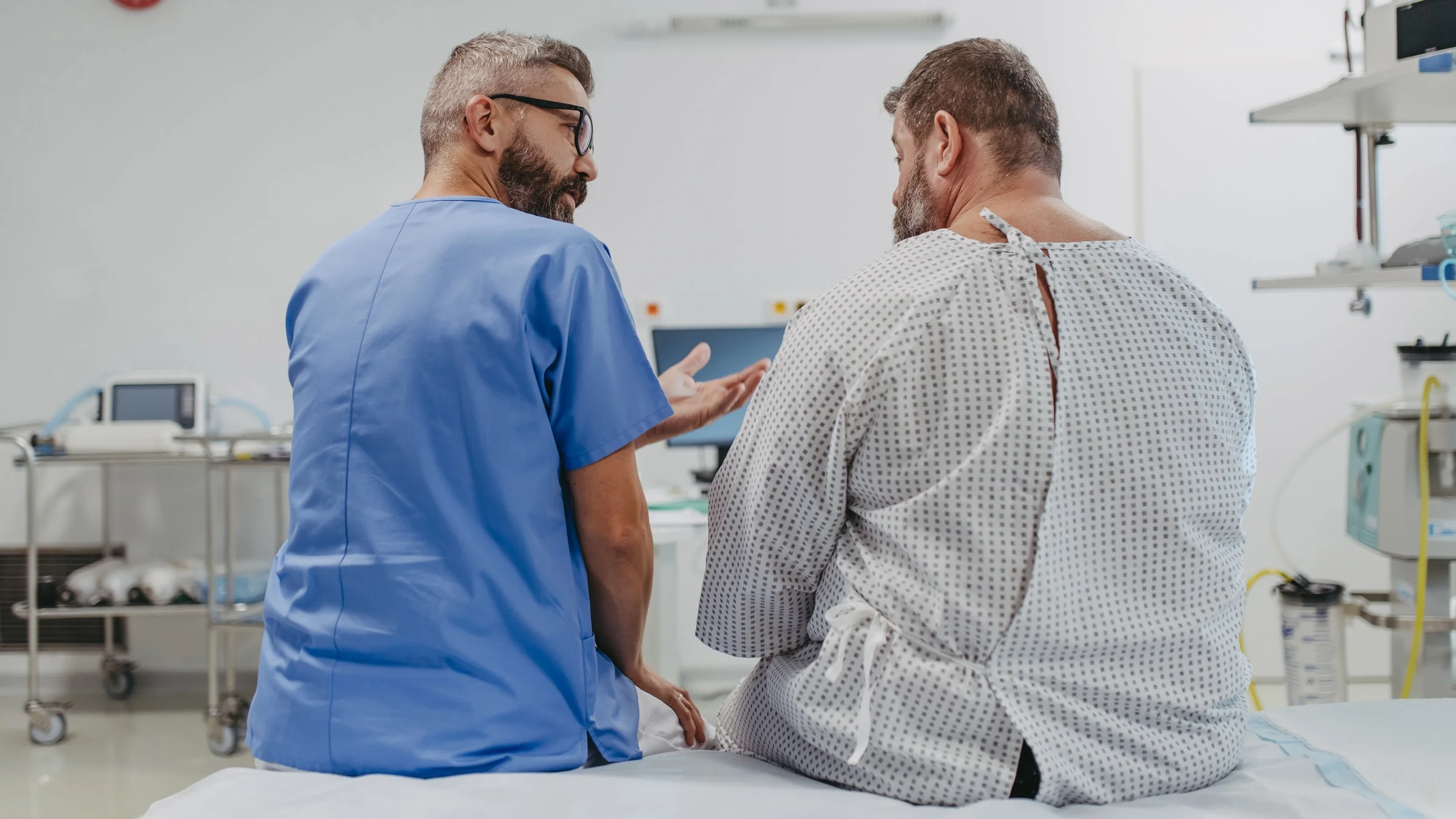 A doctor talking to a plus-size patient in a hospital gown.