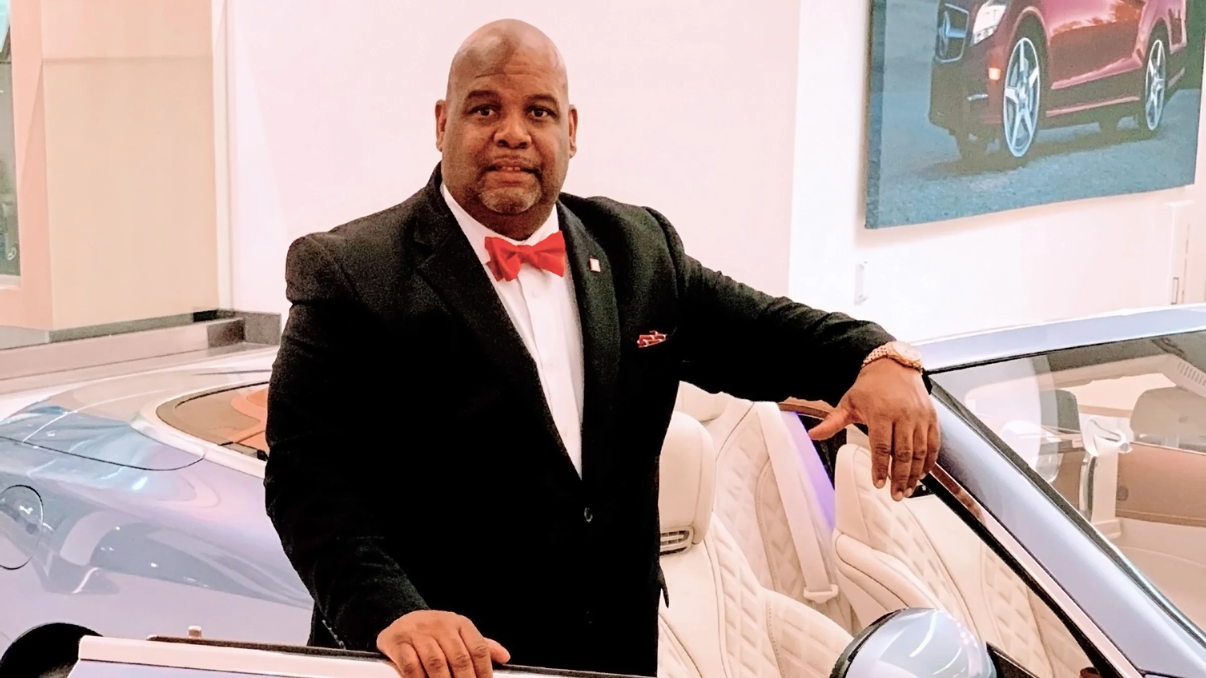 Greg Hoyd wearing a suit and leaning on a convertible car.