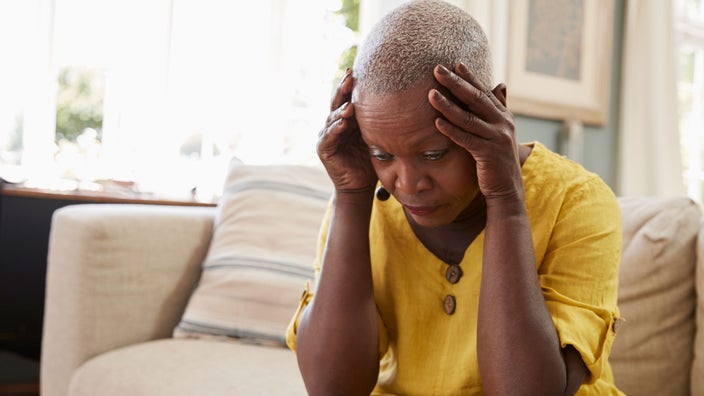 Woman on couch, head in hands.