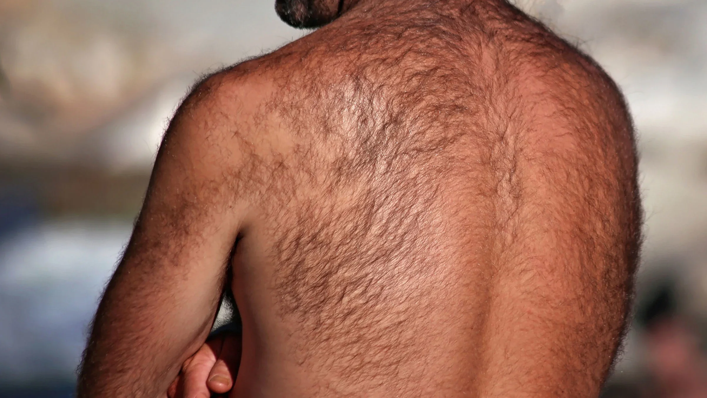 A man with a hairy back stands shirtless with his arms crossed.
graphicphoto/iStock via Getty Images Plus