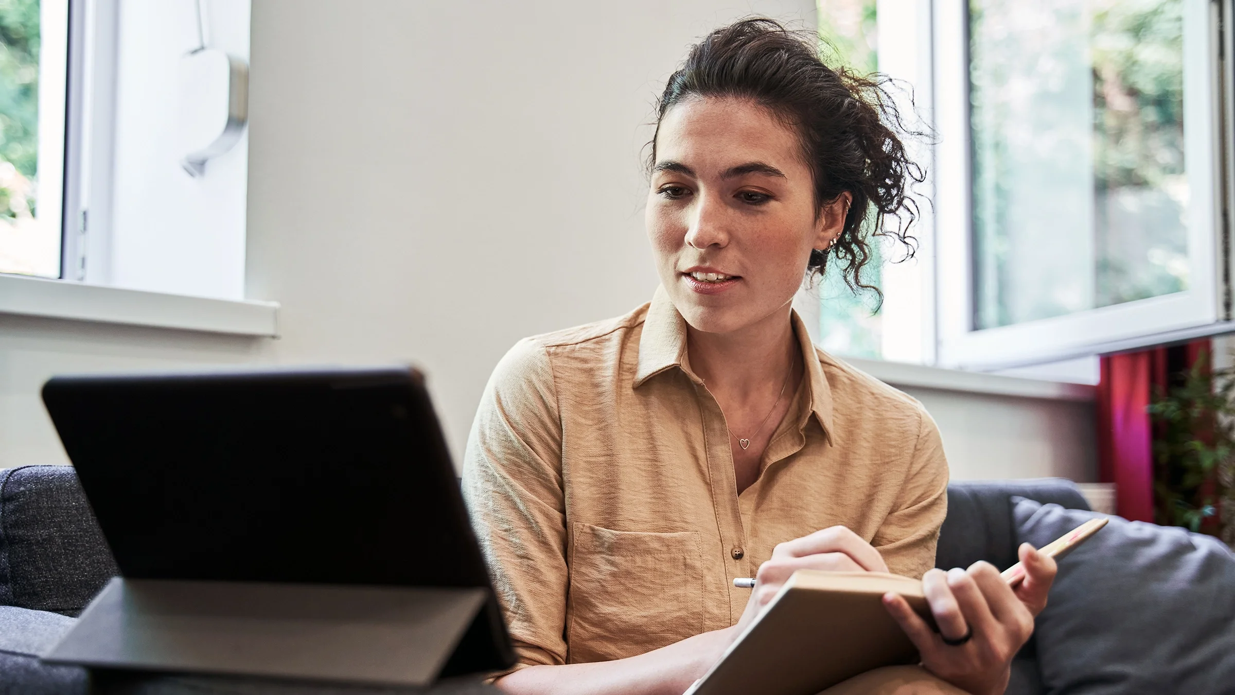 A woman is taking notes while on a virtual call.
