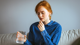 A woman prepares to take a pill with a glass of water.
dragana991/iStock via Getty Images Plus