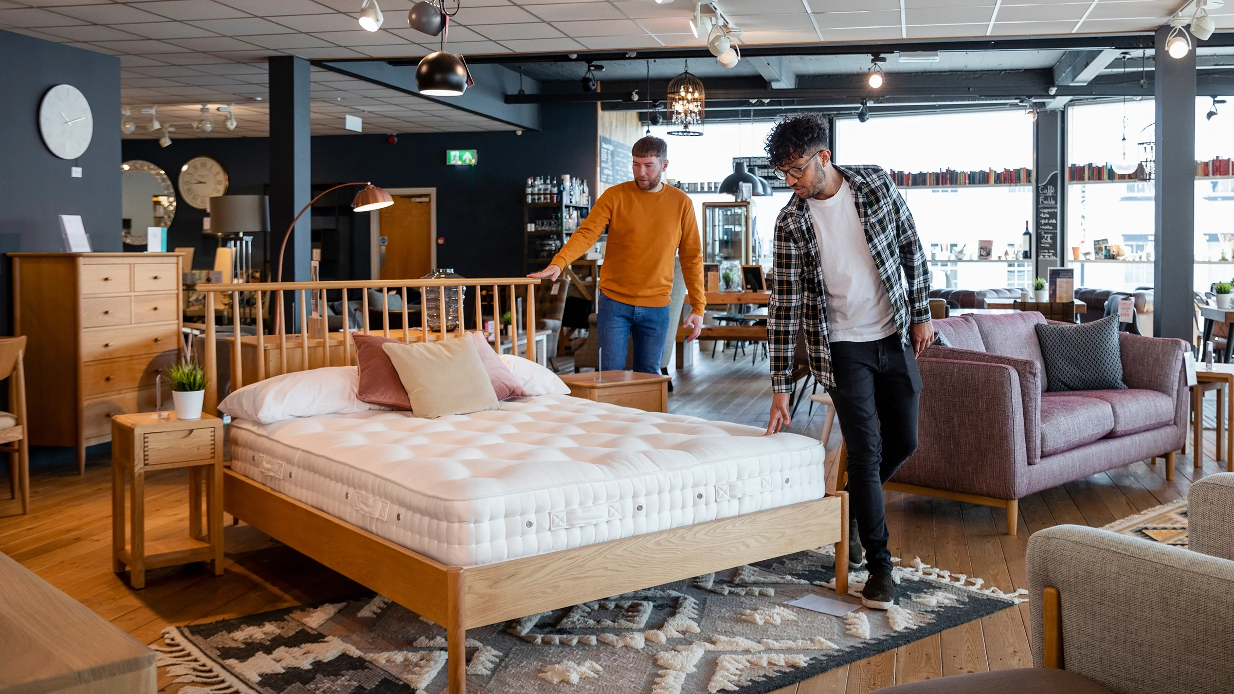 A couple is looking at a mattress in a furniture showroom.