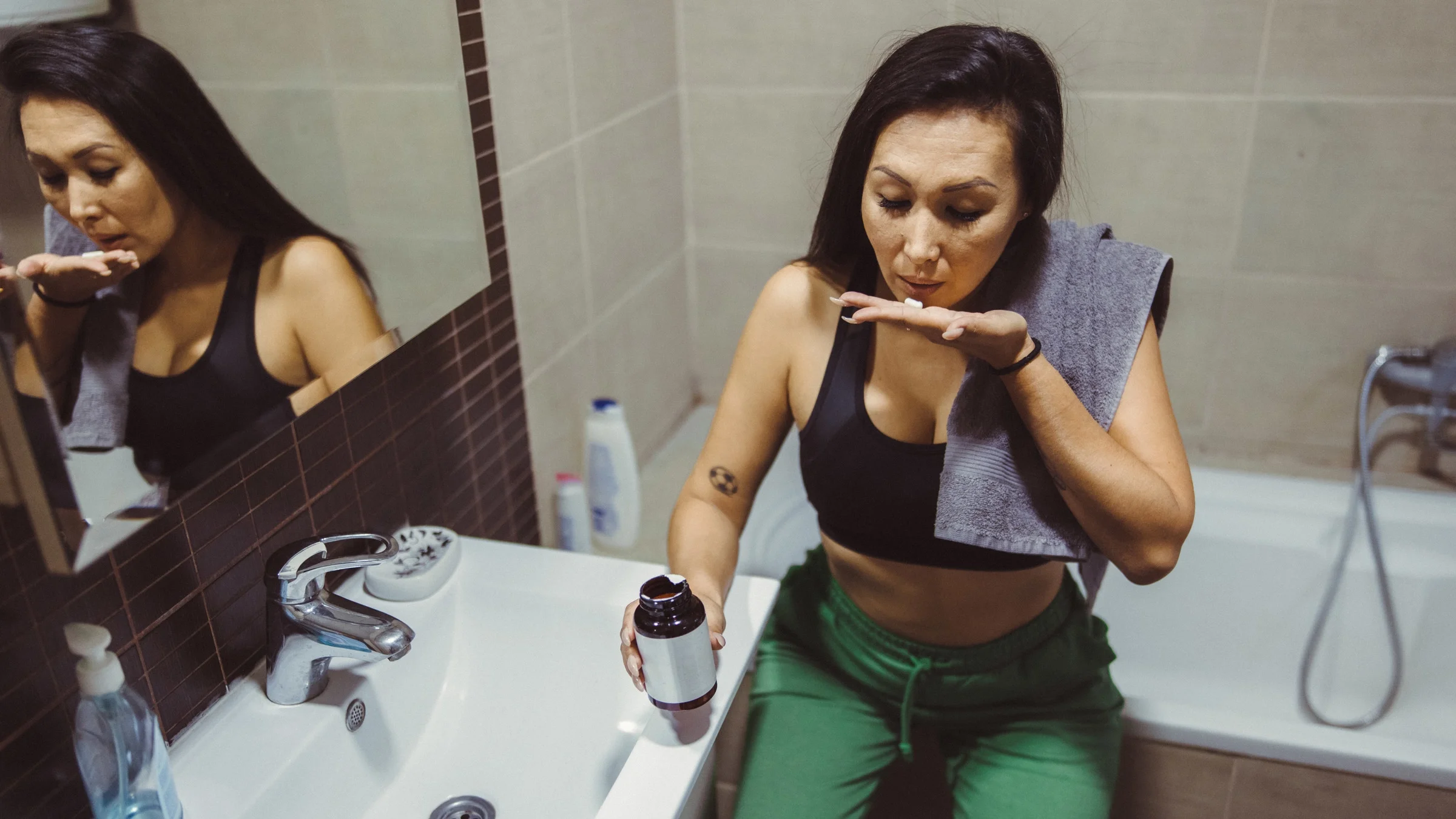 A person taking a pill in their bathroom.