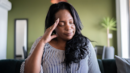 A woman, in pain, touching her head with her eyes closed. 
FG Trade/E+ via Getty Images