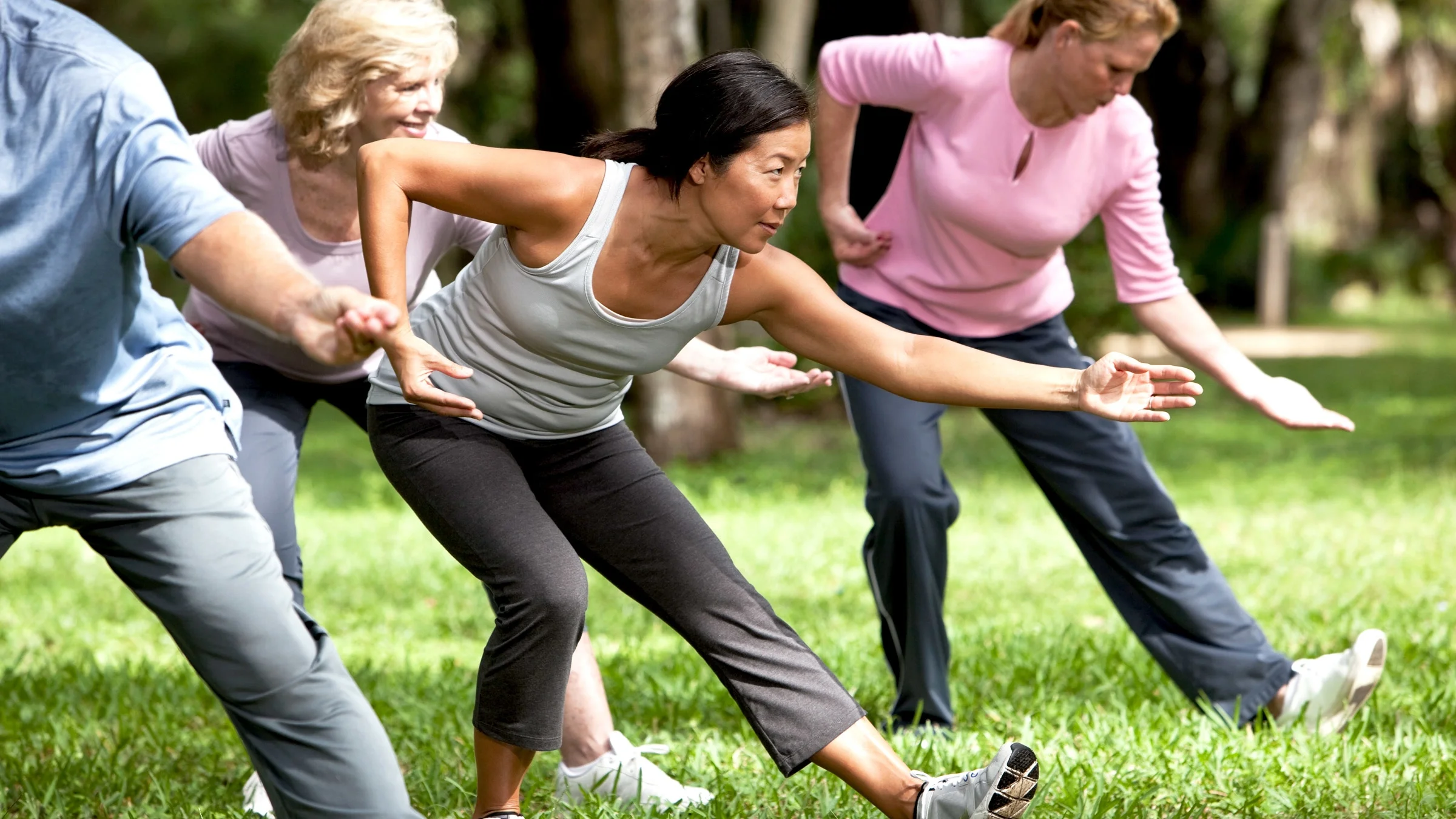 A group of people doing tai chi in a park.