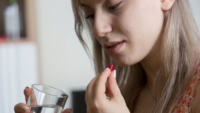 Close-up of someone taking a pill.	