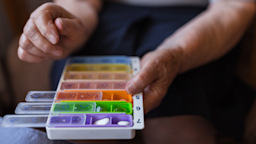 Close-up of a person putting their pill into their colorful pill organizer.
Dobrila Vignjevic/E+ via Getty Images