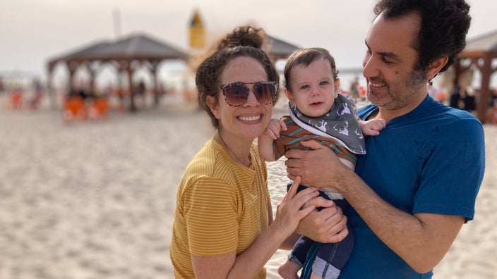 Leah Sushelsky on a beach with her husband and child.