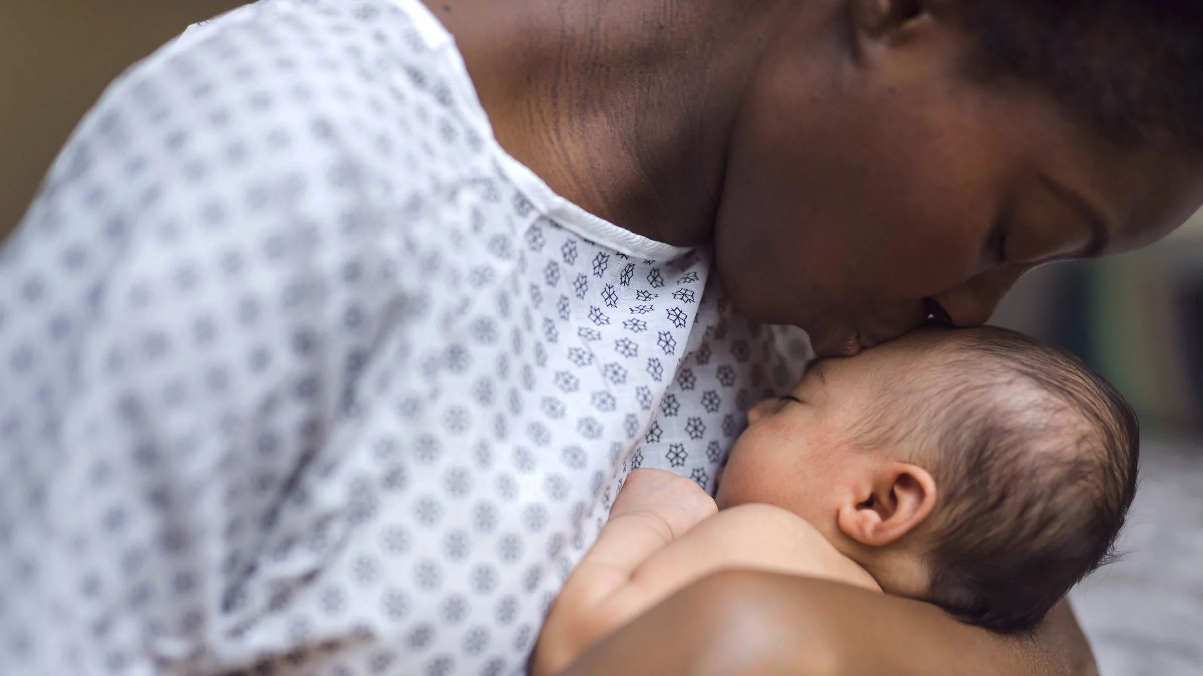 A mother is kissing her newborn baby at the hospital.