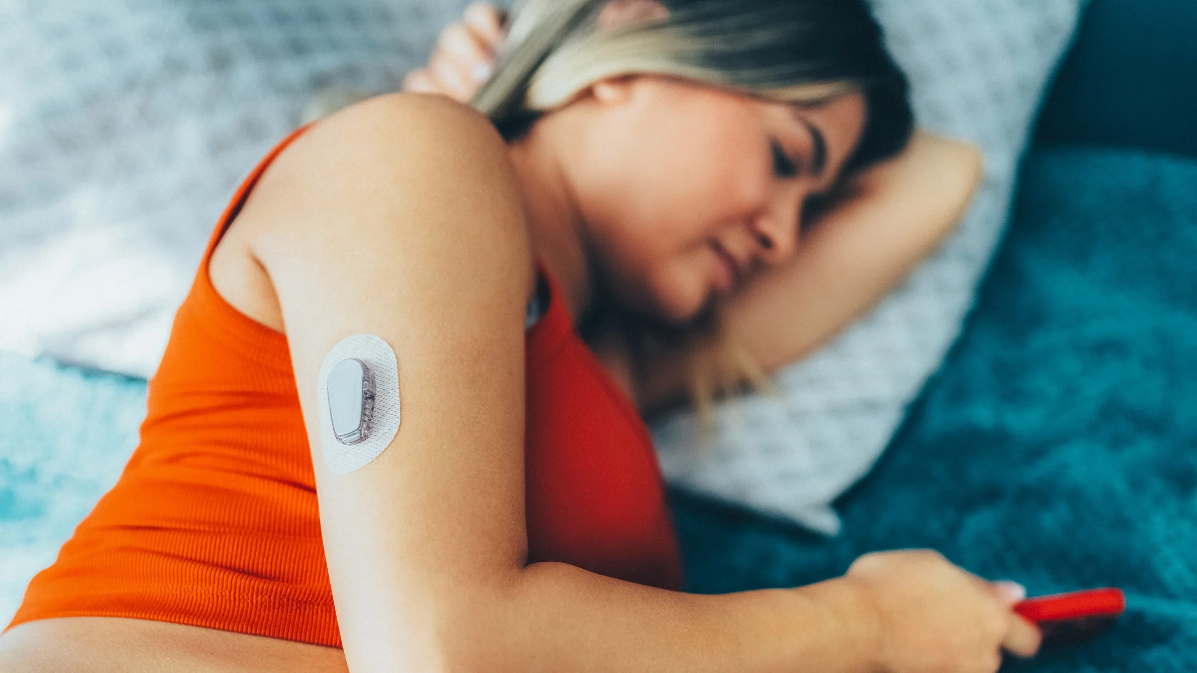 A person with a glucose monitor on their arm in bed.