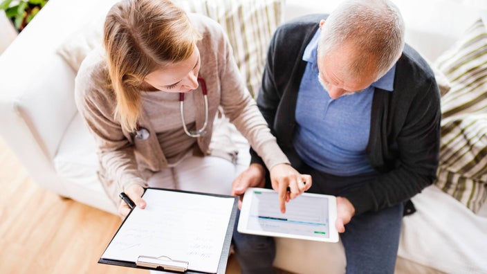 A HCP showing a tablet to a patient.