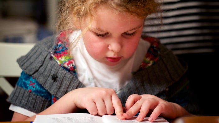 Child reading a book with her finger on a page