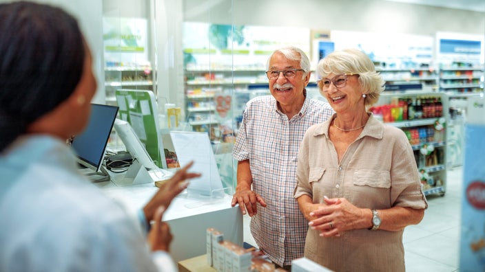 An older couple is having a friendly consultation at the pharmacy counter.
