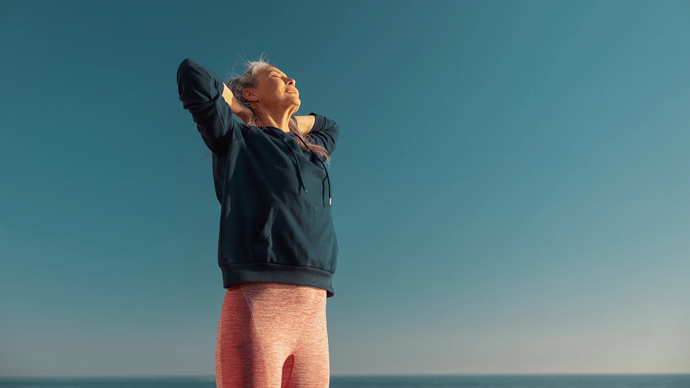 A woman with her hands behind her head is looking up on a sunny day.
Yaroslav Astakhov/iStock via Getty Images Plus
