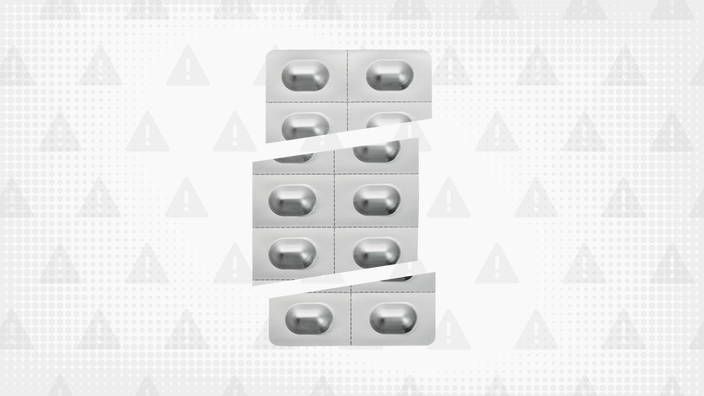 A gray background with texture and warning sign pattern. In the center is a silver blister pack of pills cut into thirds.