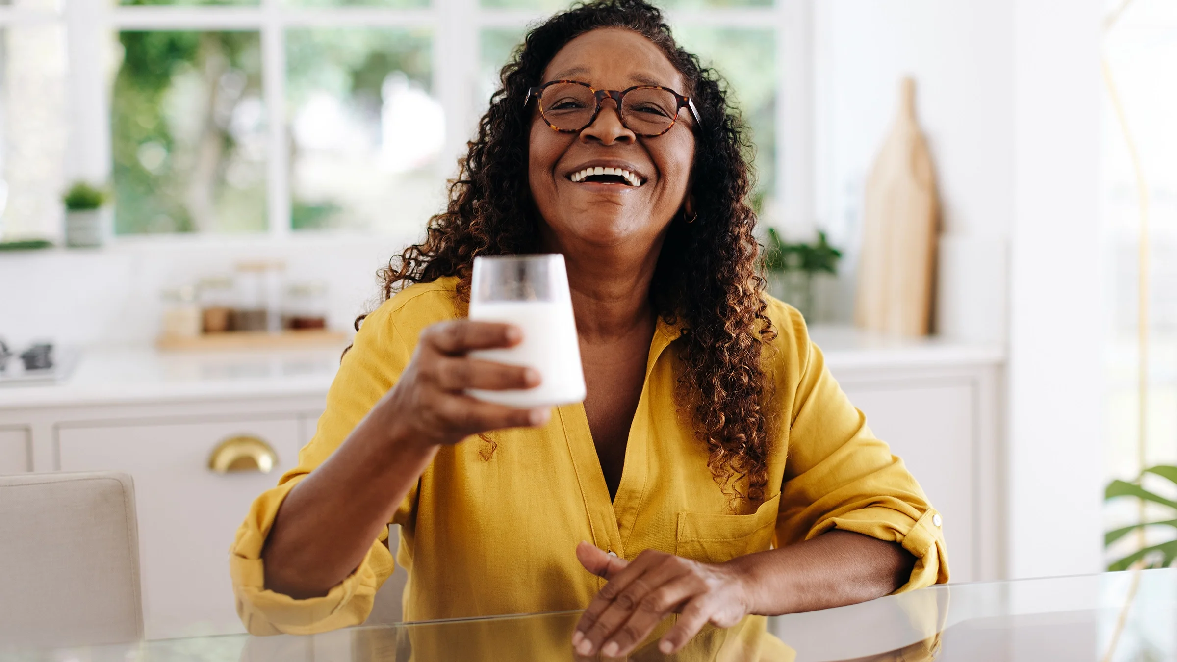 Portrait of woman smiling while holding a glass of milk.