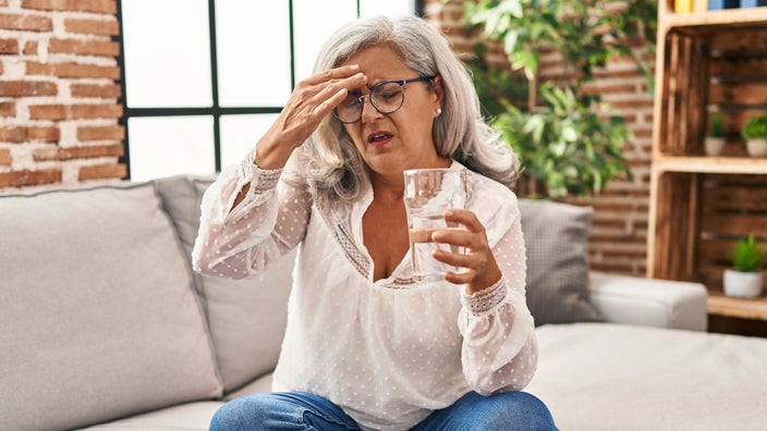 A person with a headache drinking water.