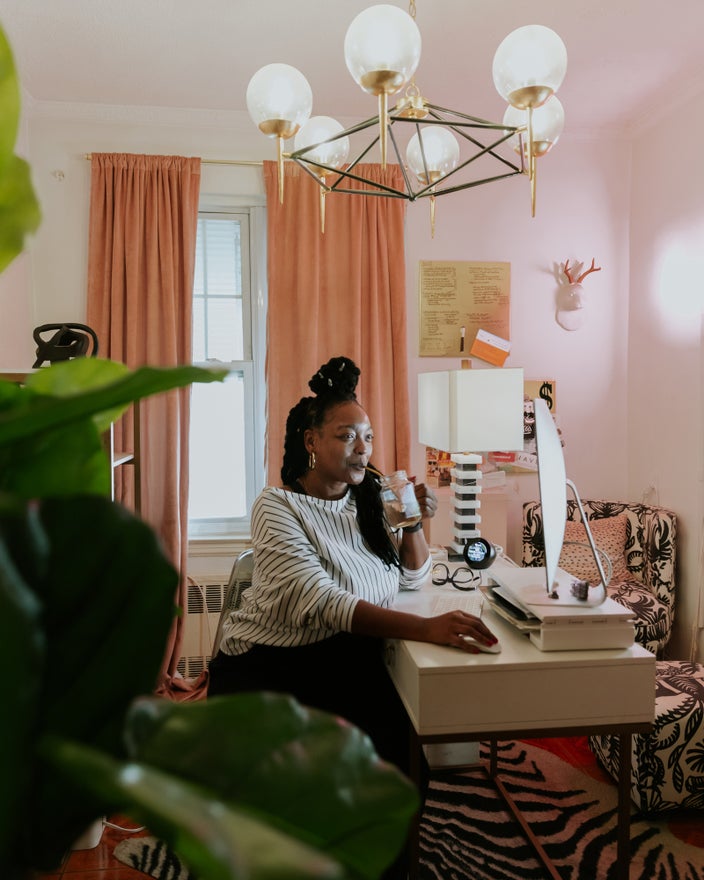 Nikki sitting at her desk at home working while having a smoothie.