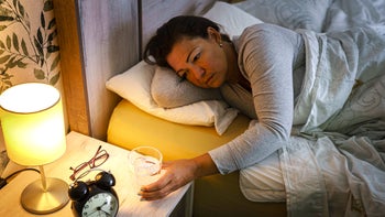Melatonin: woman drinking glass of water from bedside 1455947740