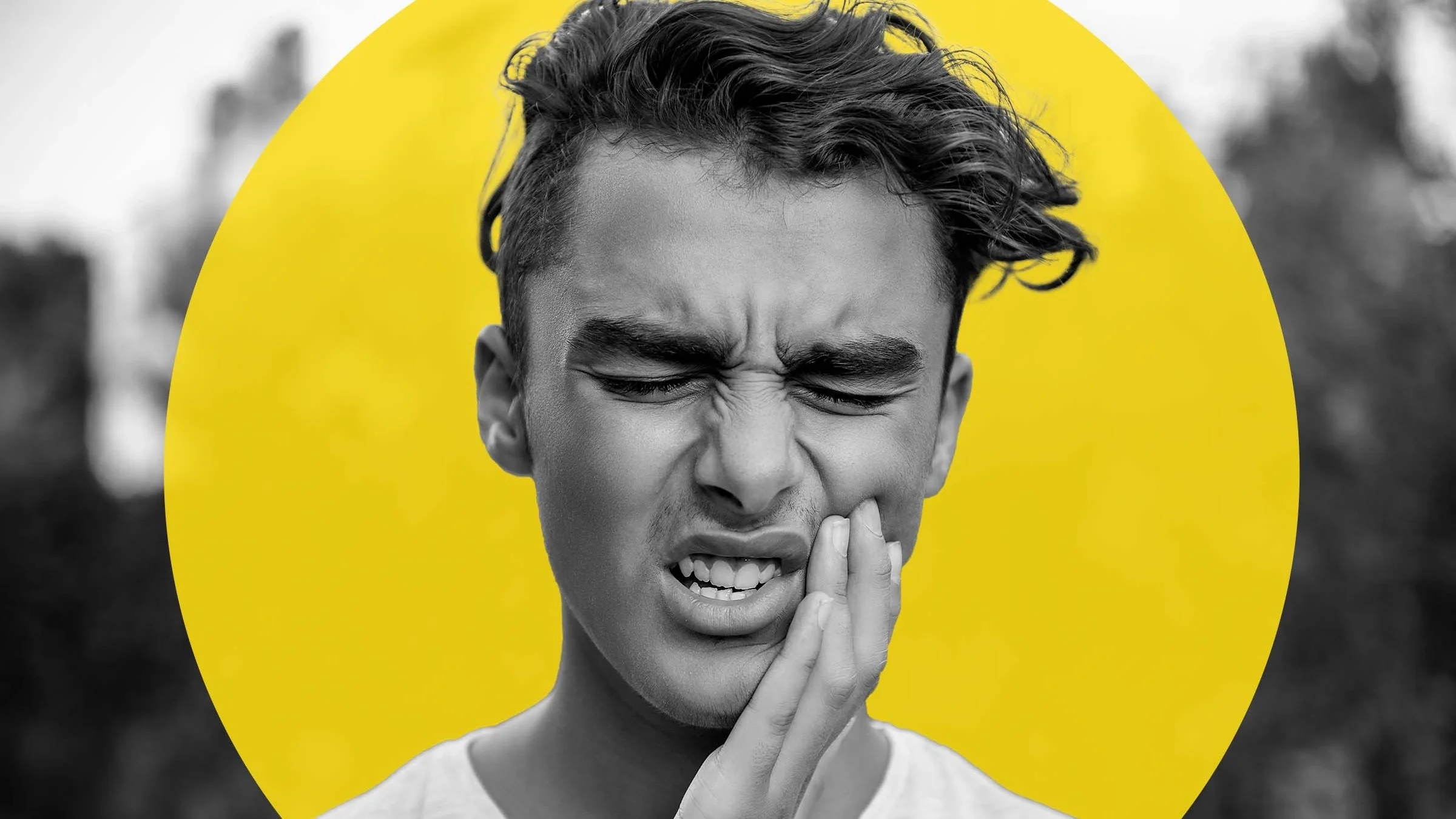 Black and white portrait of a teenage boy rubbing the side of his cheek with his hand. There is an added yellow graphic circle behind his head.