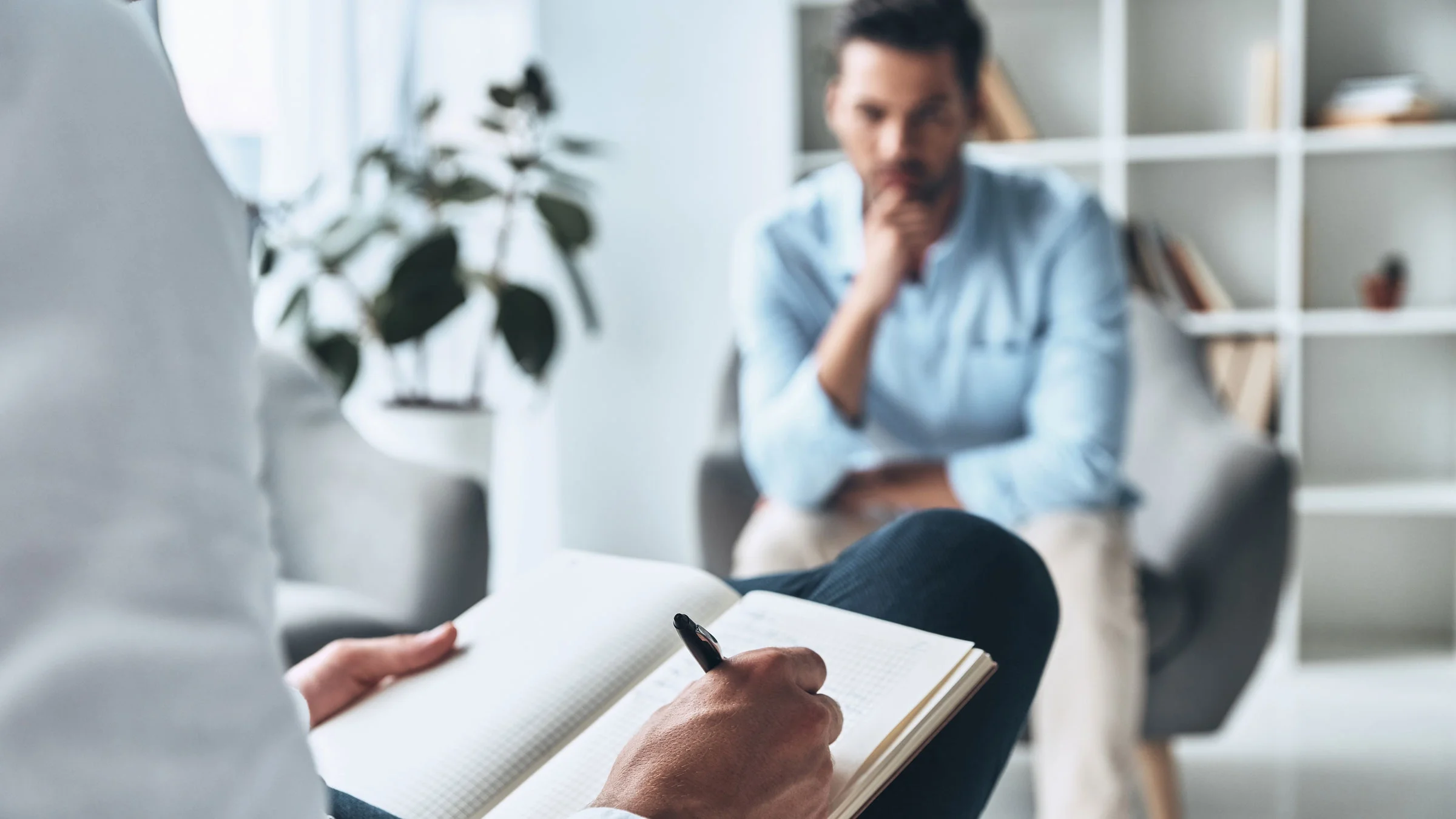 A therapist takes notes during a session with a client.