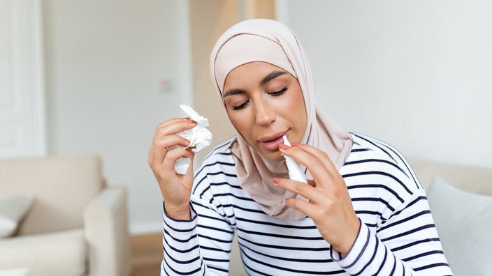 A woman uses nasal spray at home