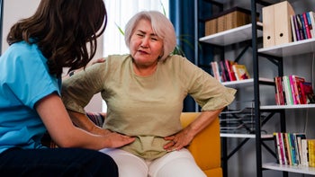 nurse helping older woma n stomach pain-1343308620
