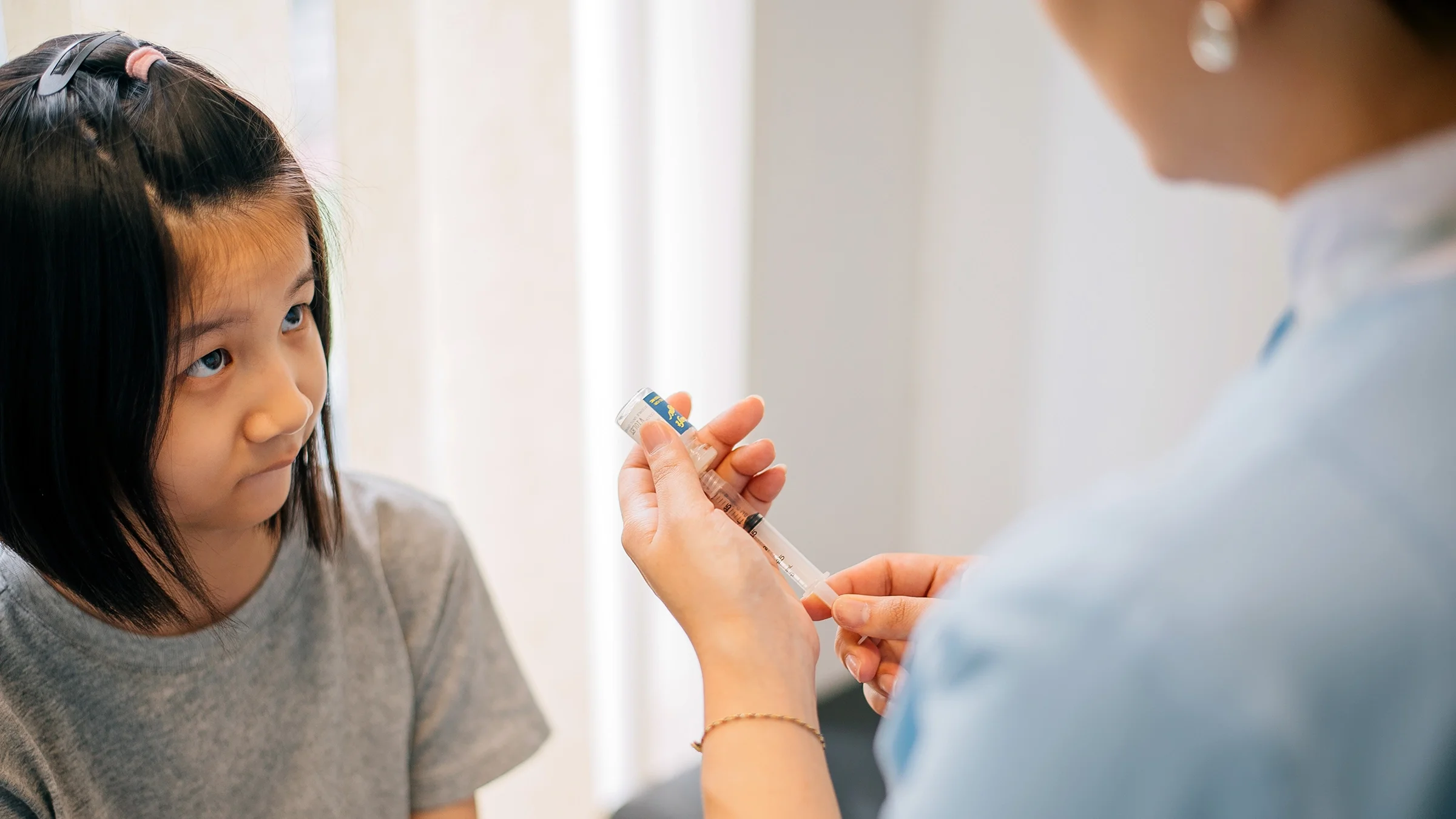 A healthcare professional prepares to give a child a vaccine.