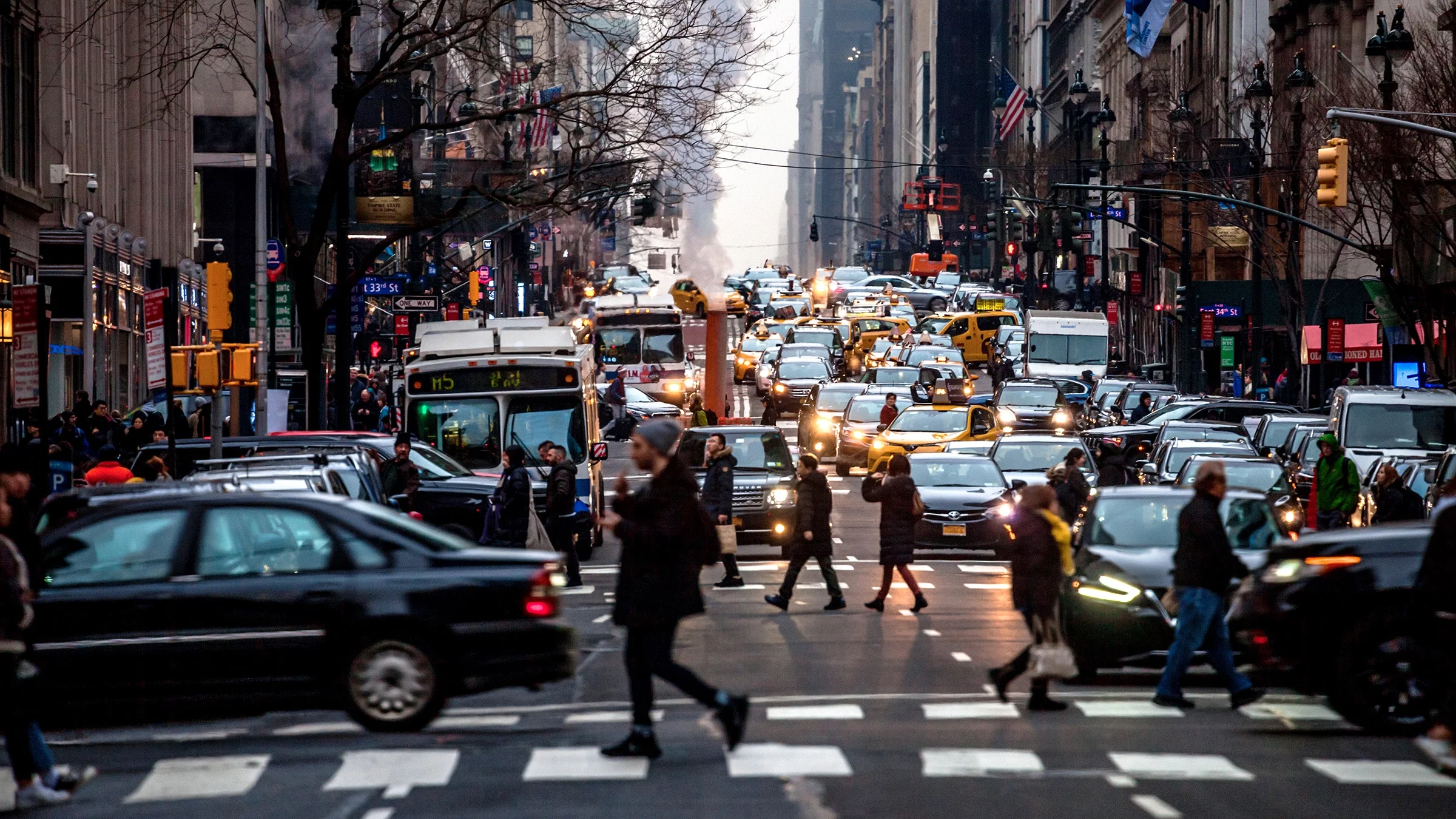 Busy New York City traffic with many pedestrians crossing the road.