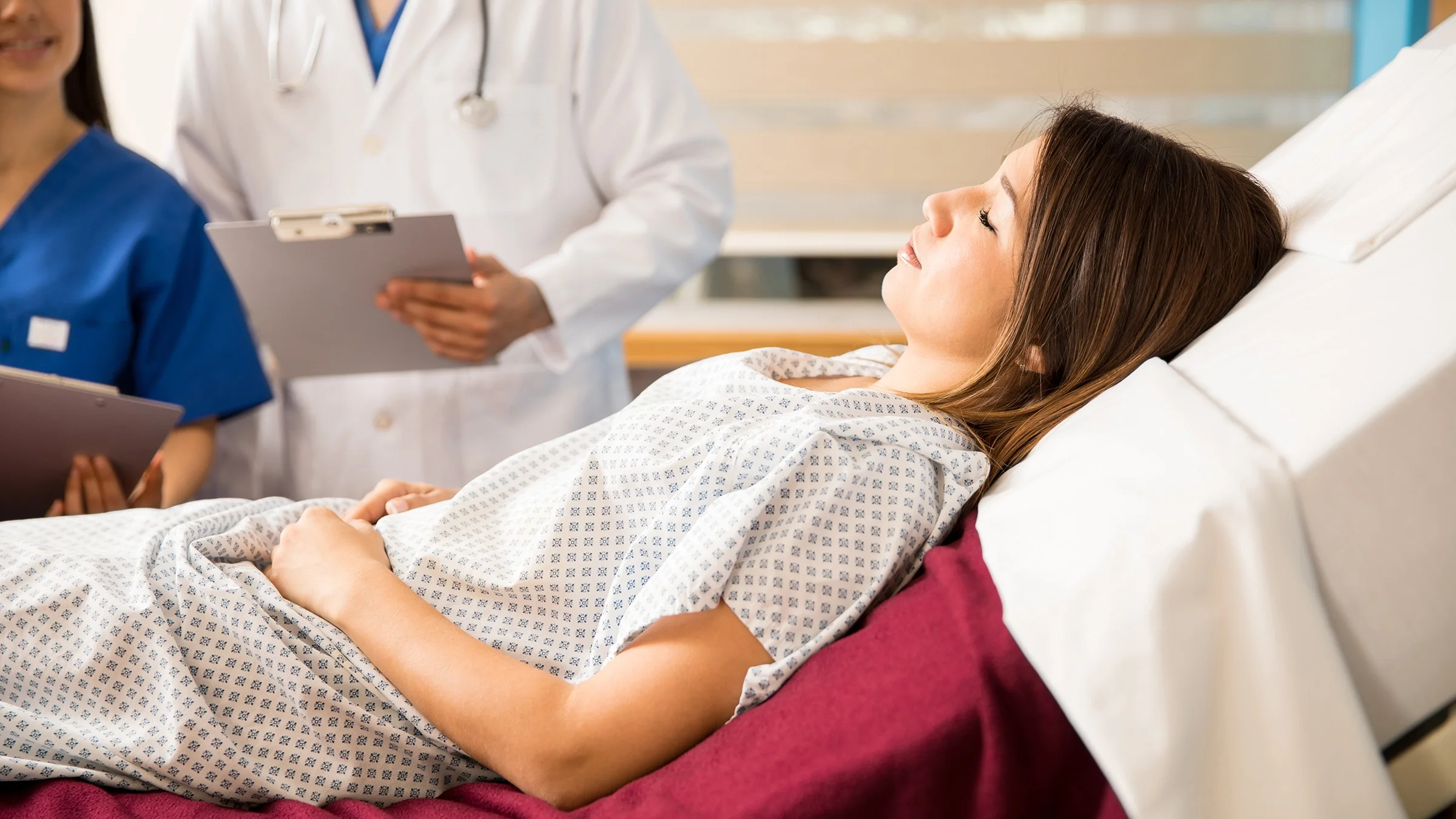 A person dressed in a hospital gown is lying on a bed.