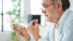 A man is taking a pill by mouth. He also has a glass of water in his hand.
seb_ra/iStock via Getty Images Plus