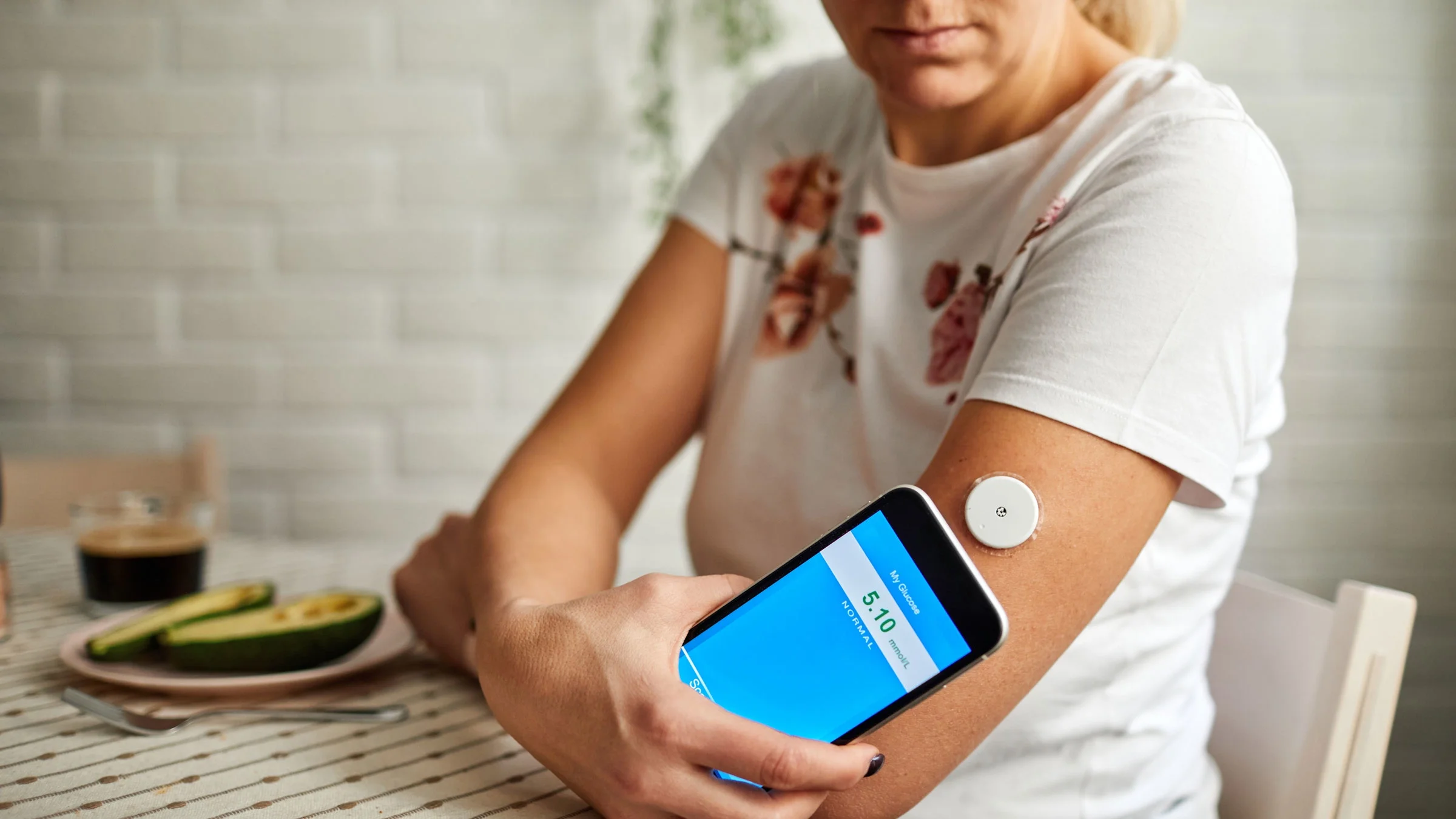 Woman swiping glucose monitor with smartphone application. 