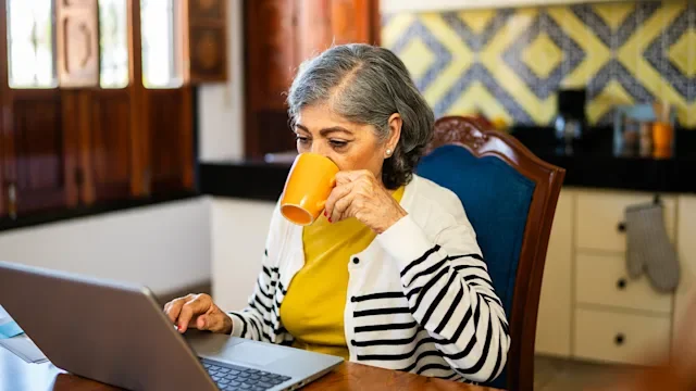 afib: woman drinking coffee while using a laptop 2173908968