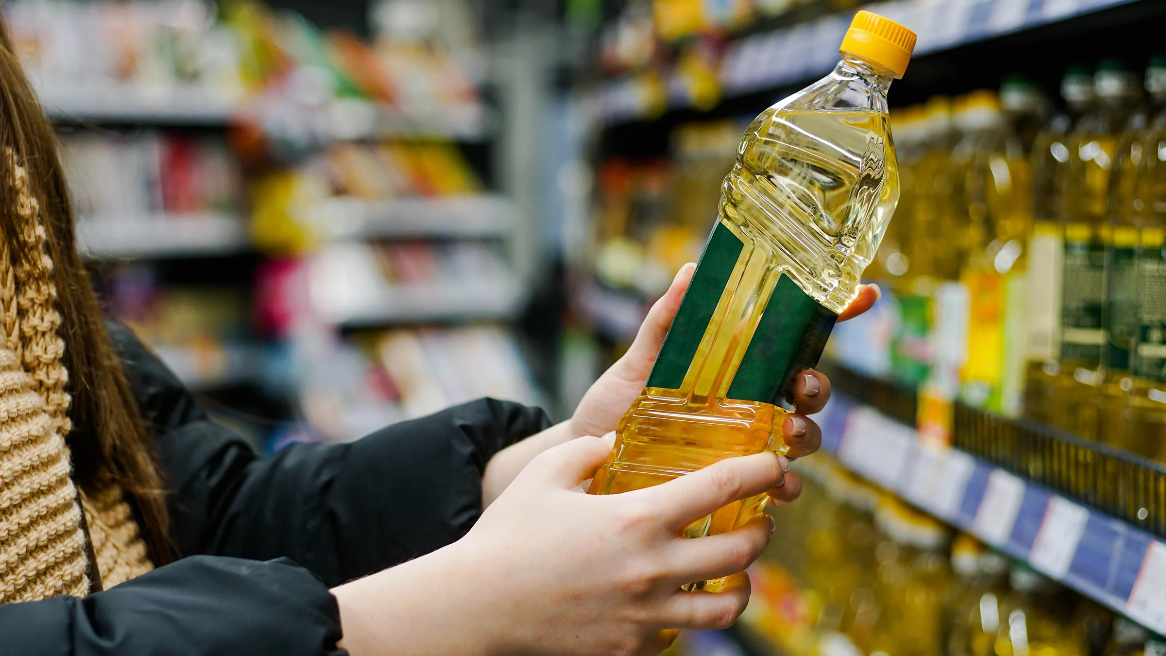 Close-up of hand holding bottle of oil at store
