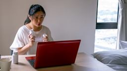 A patient holding up a pill bottle in a telehealth call.
simon2579/E+ via Getty Images 