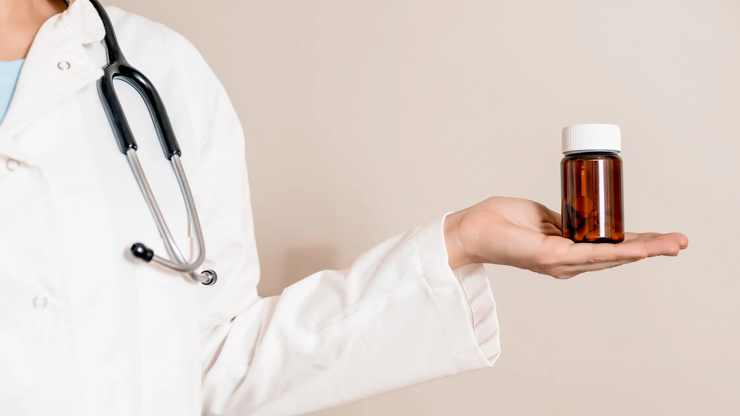 Cropped shot of a doctor holding a glass pill bottle in the palm of their hand.