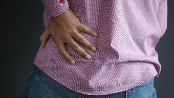 A man is holding his lower back in a close-up.
