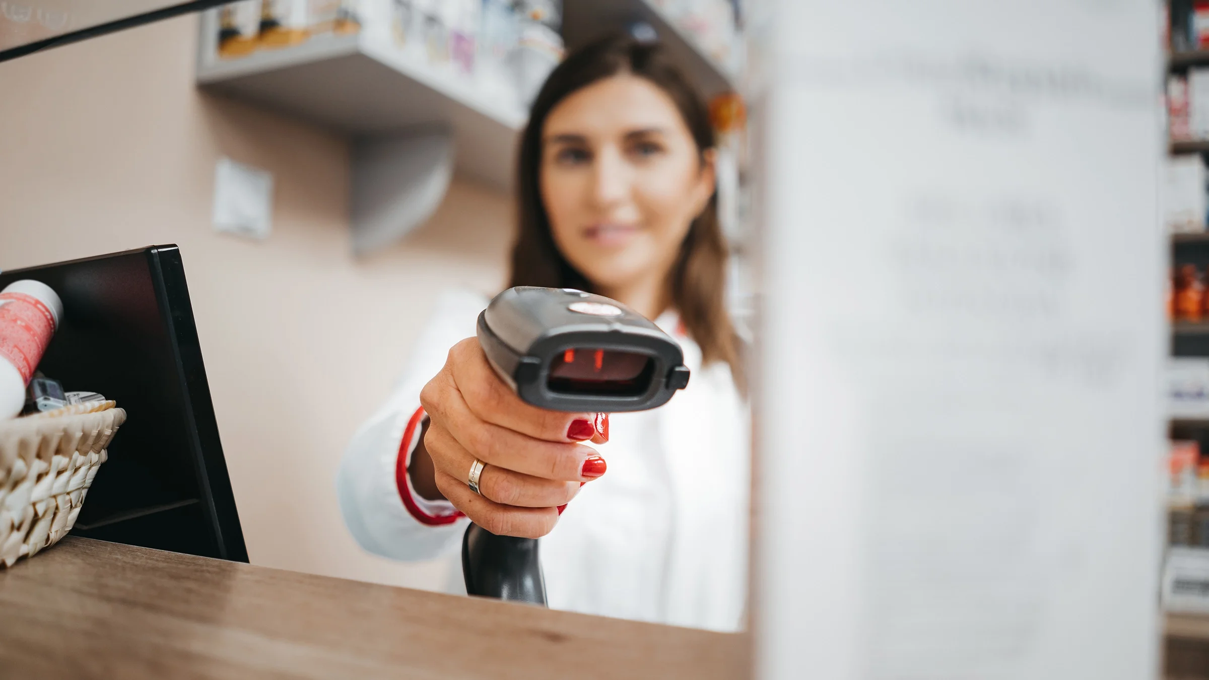A pharmacist is scanning a medication box with a price scanner. 