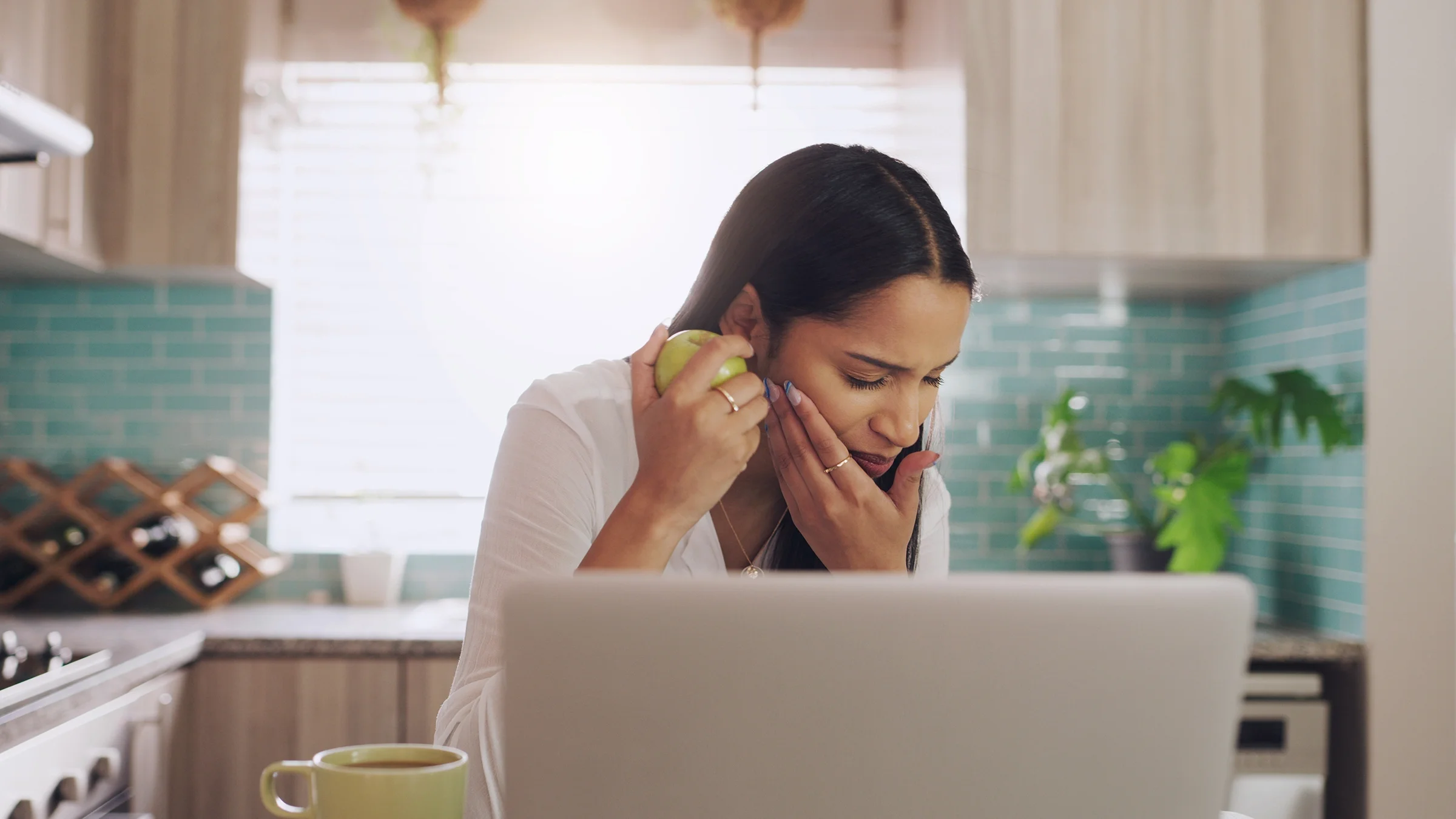 A woman has mouth pain as she’s eating an apple.
