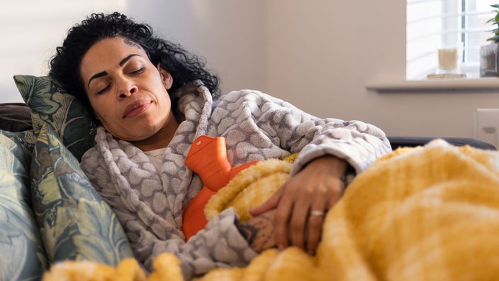 A woman sleeps with a heating pad against her belly. 
