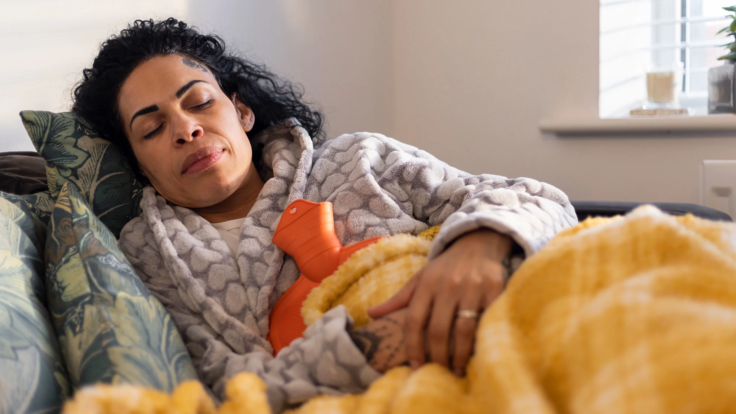 A woman sleeps with a heating pad against her belly.