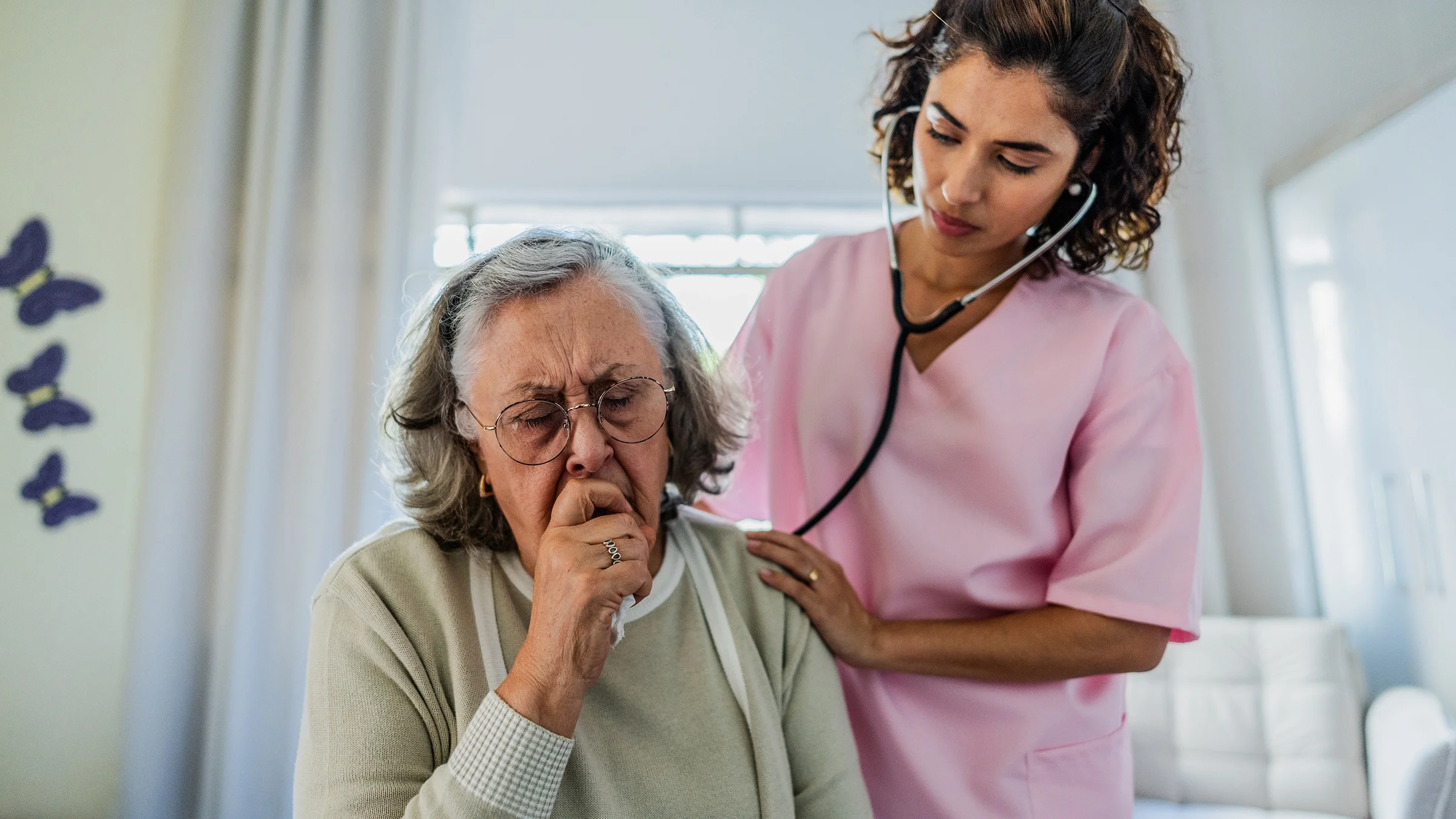 Medical professional examining an older woman with a stethoscope.