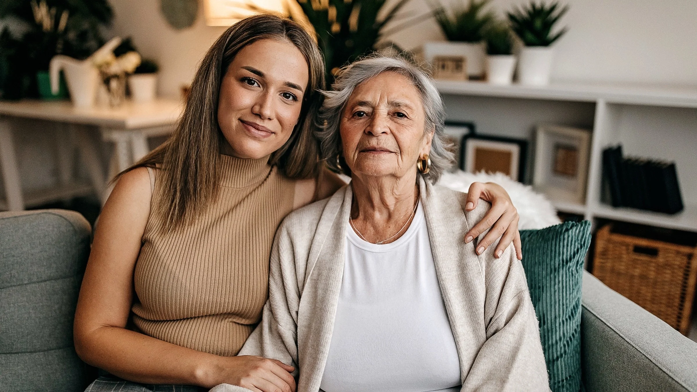 Portrait of a senior woman and her granddaughter sitting on the couch at home.