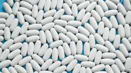 White oblong pills filling the frame. You can see a little bit of the bright blue background coming through in the cracks between the pills.
Oxana Medvedeva/iStock via Getty Images

