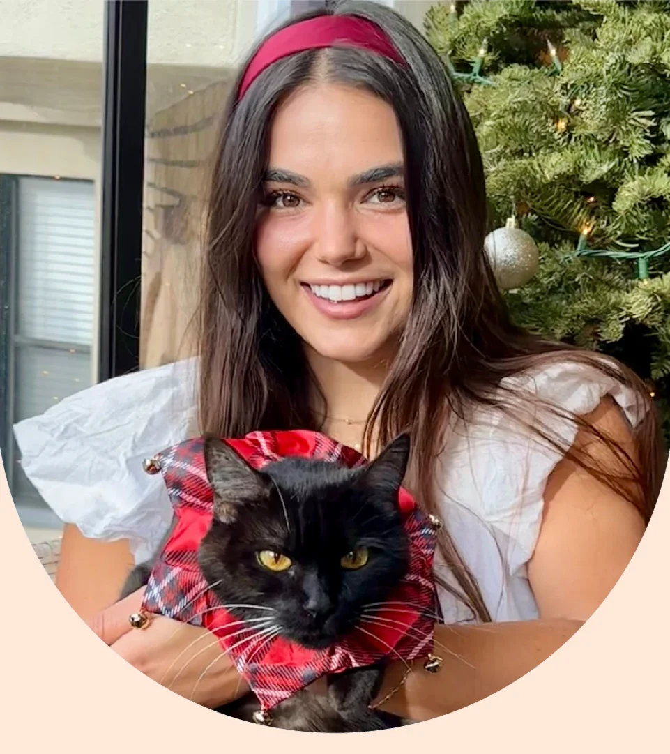 Sarah Chiappetta is pictured in a headshot, holding her beloved black cat Harper.